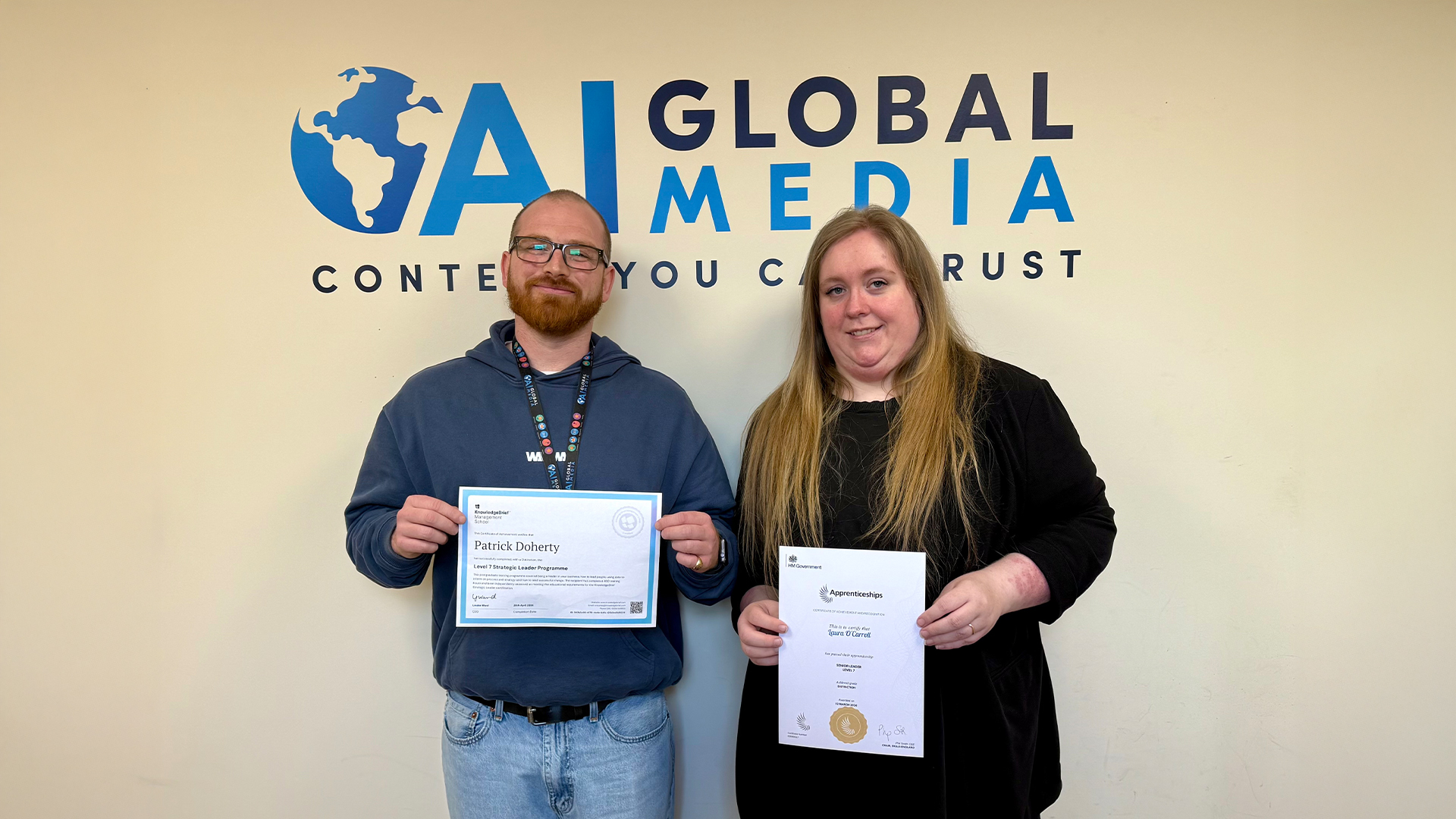2 employees smiling and holding their certificates